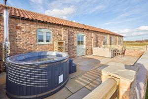 a hot tub on a patio next to a brick building at Wold's View Cottage in Yedingham
