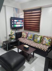 a living room with a couch and a flat screen tv at Isabelle De Valenzuela Condo Staycation in Marulas Valenzuela in Manila