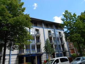 a white building with blue windows and cars parked in front at FeWo mit "Dachterrasse" im Blauen Palais Leipzig in Leipzig