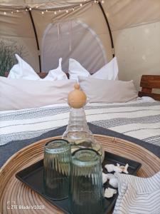 a tray with a bottle and glasses on a table in front of a bed at Glamping Altes Pastorat in Barmstedt