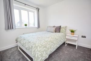 Habitación blanca con cama y ventana en Cosy,Modern and Relaxing 3 bedroom house with parking, en Mánchester
