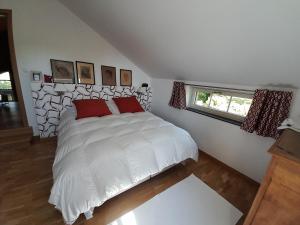 a bedroom with a white bed with two red pillows at Au Bout du Village in Stoumont