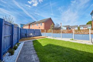a backyard with a blue fence and a table at Cosy,Modern and Relaxing 3 bedroom house with parking in Manchester
