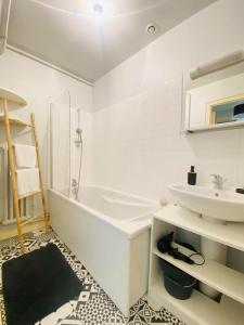 y baño con bañera blanca y lavamanos. en Coeur de ville, appartement moderne avec mezzanine, en Laon