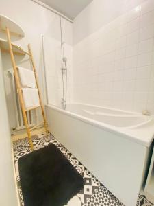 y baño con bañera y alfombra negra. en Coeur de ville, appartement moderne avec mezzanine, en Laon