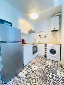 eine Küche mit einem Kühlschrank und einem schwarz-weißen Boden in der Unterkunft Coeur de ville, appartement moderne avec mezzanine in Laon
