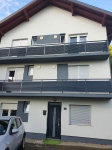 een wit gebouw met zwarte balkons en een auto aan de voorkant bij Elem apartmani in Tuzla