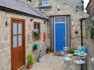a stone house with blue doors and a patio at The Old Telephone Exchange in Rothbury
