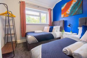 2 camas en una habitación con paredes azules y ventana en Stunning House Free Parking Garden WiFi en Bristol