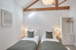 two beds in a room with white walls and wooden beams at Rose Cottage in Yedingham
