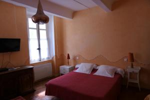 1 dormitorio con cama roja y ventana en la métairie de Martine en Riez