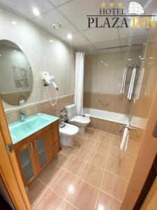 a bathroom with a toilet and a tub and a sink at Hotel Plaza Inn in Figueres