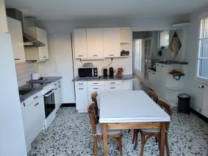 een keuken met witte kasten en een tafel en stoelen bij Bléré maison centre ville proche Beauval et Chenonceau in Bléré