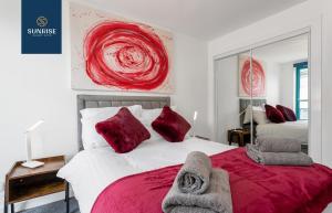 a bedroom with a bed with red pillows at THE PENTHOUSE, Spacious, Stunning Views, Foosball Table, 3 Large Rooms, Central Location, River Front, Tay Bridge, V&A, 2 mins to Train Station, City Centre, Lift Access, Parking, WiFi, Mid-Stay Rates Available by SUNRISE SHORT LETS in Dundee