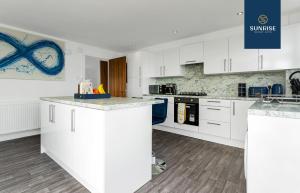a kitchen with white cabinets and a counter top at THE PENTHOUSE, Spacious, Stunning Views, Foosball Table, 3 Large Rooms, Central Location, River Front, Tay Bridge, V&A, 2 mins to Train Station, City Centre, Lift Access, Parking, WiFi, Mid-Stay Rates Available by SUNRISE SHORT LETS in Dundee