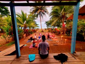 a group of people sitting in a yoga class on the beach at TORTUGA BAY Eco Hotel in El Valle