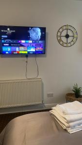 einen Flachbild-TV an der Wand mit einer Uhr in der Unterkunft Bv Comfy Studio At Deighton Huddersfield in Huddersfield