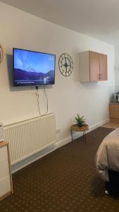 Bv Comfy Studio At Deighton Huddersfield في هدرسفيلد: غرفة نوم مع تلفزيون بشاشة مسطحة على الحائط