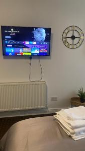 a flat screen tv hanging on a wall with a clock at Bv Comfy Studio At Deighton Huddersfield in Huddersfield