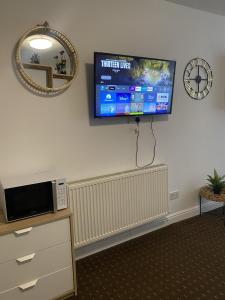 einen Flachbild-TV an der Wand eines Zimmers in der Unterkunft Bv Comfy Studio At Deighton Huddersfield in Huddersfield