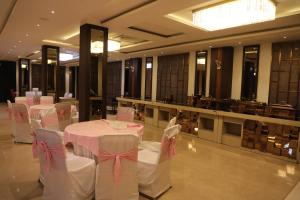 a banquet hall with white tables and chairs with pink bows at Paras inn in Gurgaon