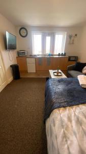 1 dormitorio con cama, sofá y reloj en Bv Cosy Studio Eleven At Deighton Huddersfield, en Huddersfield