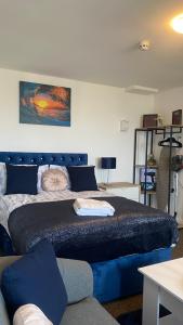 a bedroom with a blue bed with a couch at Bv Cosy Studio Eleven At Deighton Huddersfield in Huddersfield