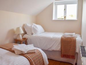 a small bedroom with two beds and a window at Rowan Cottage in Aislaby