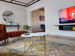 een woonkamer met een tafel en een televisie bij The Nest Airbnb - Milimani, Kitale in Kitale