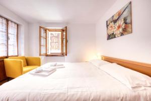 1 dormitorio con 1 cama blanca grande y 1 silla amarilla en Incanto Walser Apartments Piazza, en Macugnaga