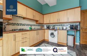 a kitchen with wooden cabinets and a washing machine at DUPLEX - 5 Bed Rooms, Amazing Views, Fully Equipped, Free Parking, WiFi, FAVOURITE for Groups & Businesses, Food, Bars, Shops, Library, River Views, by SUNRISE LONG LETS and SERVICED ACCOMMODATION DUNDEE in Dundee