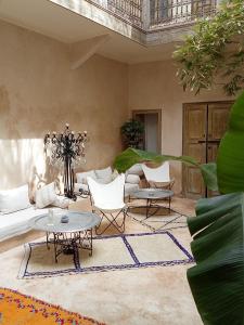 uma sala de estar com um sofá, cadeiras e mesas em Dar al Sultan em Marrakech