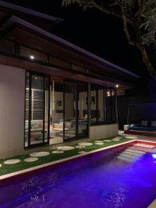 a swimming pool in front of a house at night at Kiss Bali Villas in Seminyak