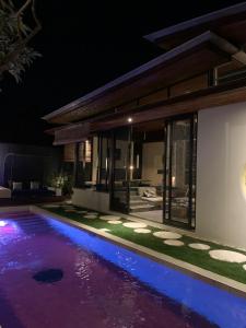 a swimming pool in front of a house at night at Kiss Bali Villas in Seminyak