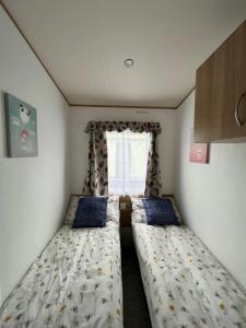 two beds in a small room with a window at JS Holidays Tebay Lagganhouse in Ballantrae