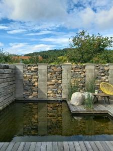 einen Teich mit einer Bank und einer Steinmauer in der Unterkunft VIGEO lounge b&b coffee in Bojnice
