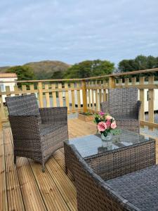a deck with two chairs and a table with flowers on it at JS Holidays Tebay Lagganhouse in Ballantrae