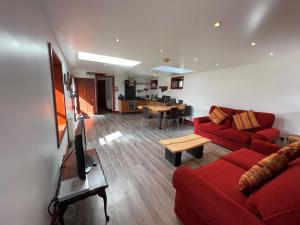 a living room with a red couch and a tv at Anne's Cottage in Bargrennan