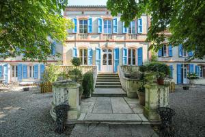 a large house with blue windows and stairs in front at Le Manoir du Thouron in Saint-Sulpice