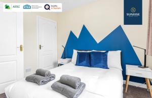 a bedroom with a bed with a blue headboard at THE TOWNHOUSE, 4 Rooms Large Beds, Poker Table, Fully Equipped, Easy Ring-Road Access, Parking, WiFi, Long Stay Rates Available by SUNRISE SHORT LETS in Dundee