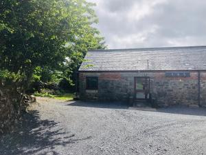 an old brick building with a gravel road next to it at Maberry Cottage in Bargrennan