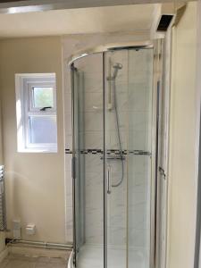 a glass shower in a bathroom with a window at Hollybush Guest House in Oxford