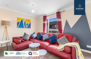 a living room with a red couch and blue pillows at THE TOWNHOUSE, 4 Rooms Large Beds, Poker Table, Fully Equipped, Easy Ring-Road Access, Parking, WiFi, Long Stay Rates Available by SUNRISE SHORT LETS in Dundee