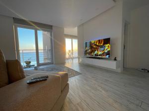 Il comprend un salon doté d'un canapé et d'une télévision à écran plat. dans l'établissement Durres Currila Modern Luxury STUNNING Beach Views, à Durrës