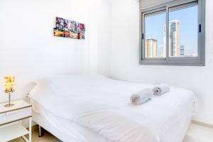 a white bedroom with a white bed and a window at Luxury Sea Side 3BR by Airsuite in Ashdod