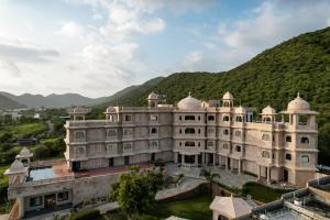an old building with a mountain in the background at Traavista Aravali Mahal in Udaipur