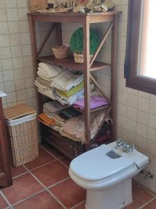 uma casa de banho com WC e uma prateleira com toalhas em Casa Rural La Torreta en El Rincón de Ademuz em Castielfabib