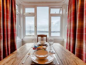 a wooden table with plates and wine glasses in a room with windows at Forth Reflections in Queensferry