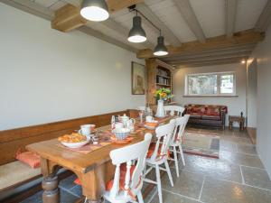 Lyndhurst Cottage في كارلتون: غرفة طعام مع طاولة خشبية وكراسي بيضاء