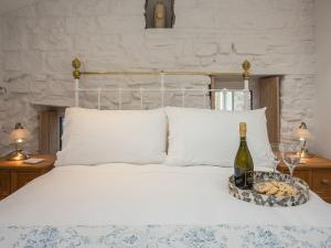 Lyndhurst Cottage في كارلتون: سرير مع زجاجة من النبيذ وصينية من الكعك